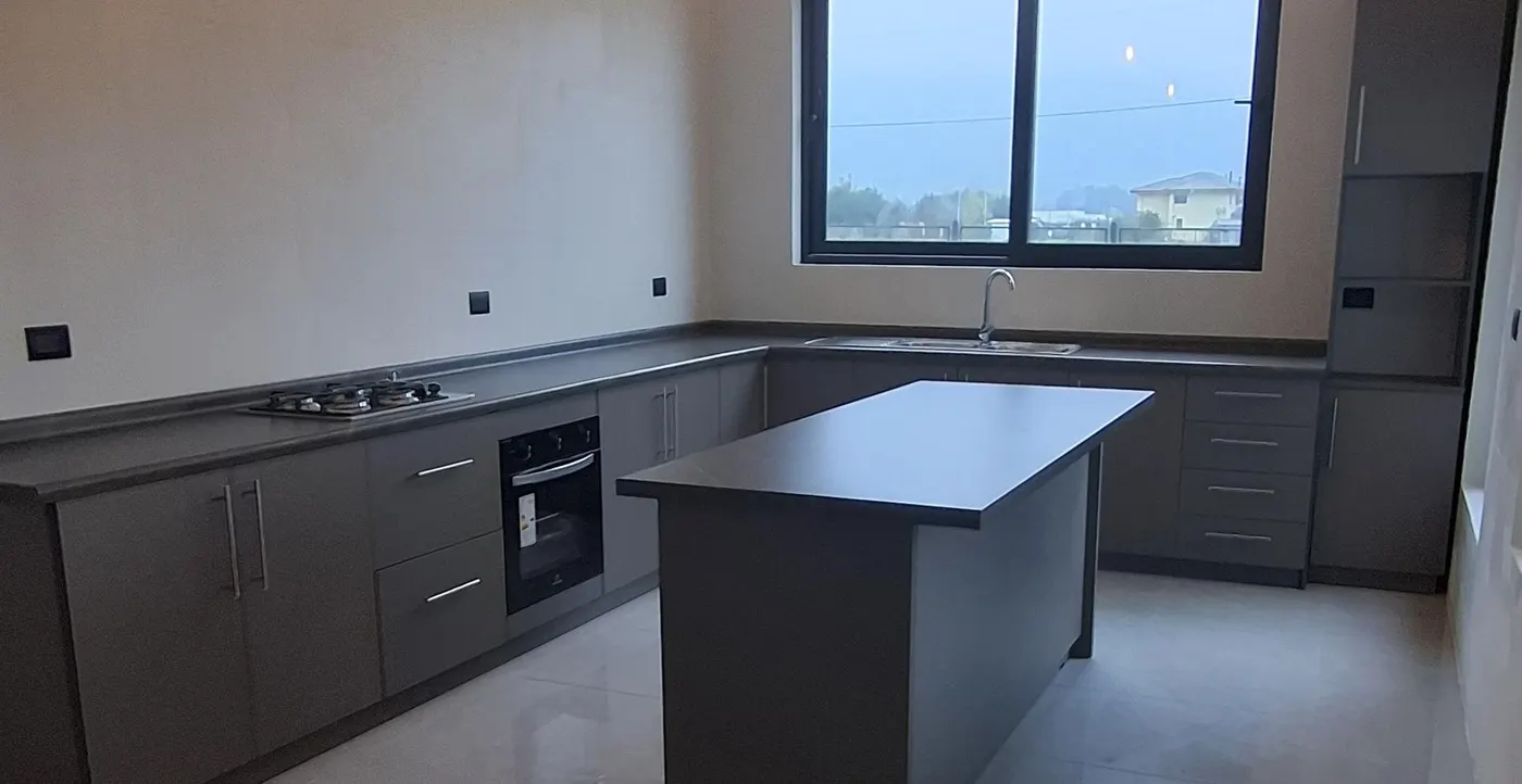 Cocina en L con isla central en tono gris oscuro y cubierta clara